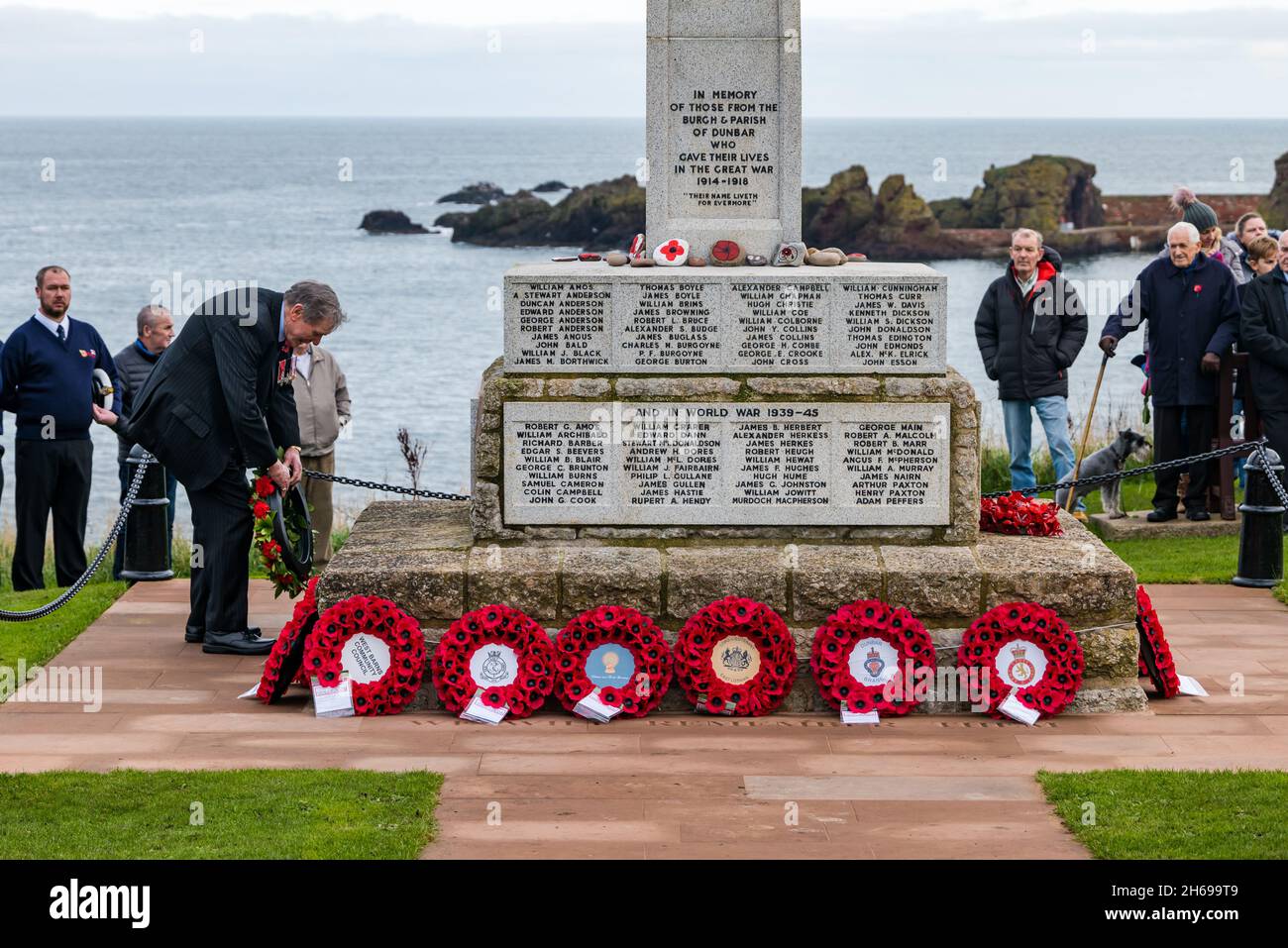 Dunbar, East Lothian, Écosse, Royaume-Uni, 14 novembre 2021.Le jour du souvenir : un service commémoratif à la cérémonie du mémorial de guerre et de la pose de couronnes.Un homme dépose une couronne de pavot au mémorial Banque D'Images