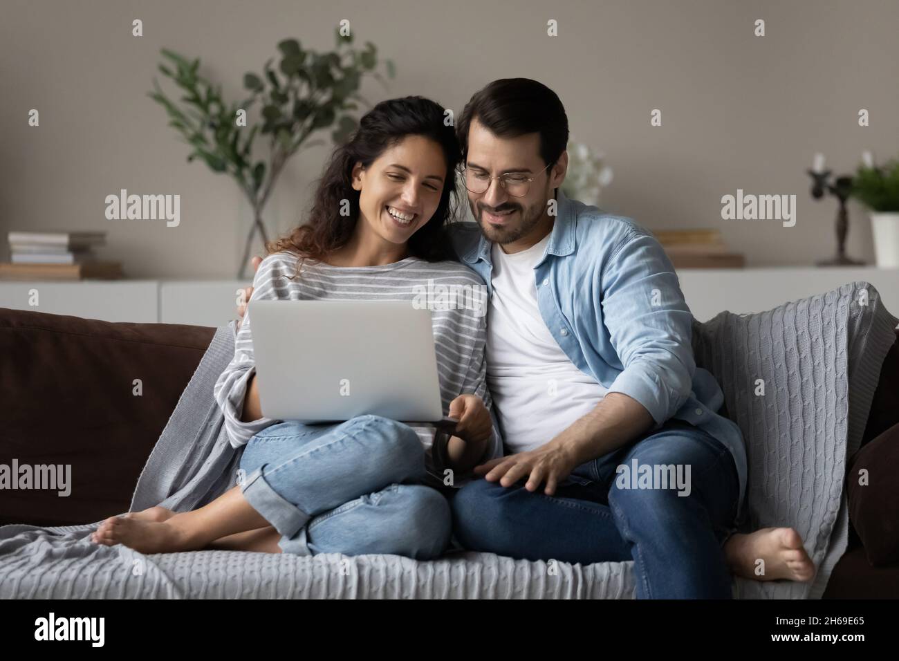 Un jeune couple heureux utilisant un ordinateur portable, se reposant sur un canapé ensemble Banque D'Images