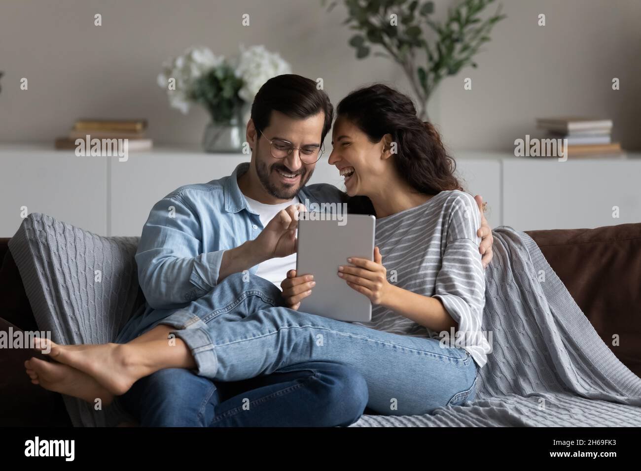 Couple riant heureux de s'amuser avec une tablette à la maison ensemble Banque D'Images