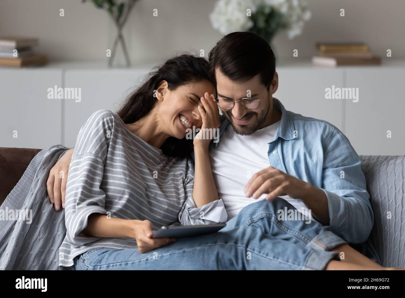 Un homme heureux et une femme en train de rire se serrer, en utilisant une tablette ensemble Banque D'Images