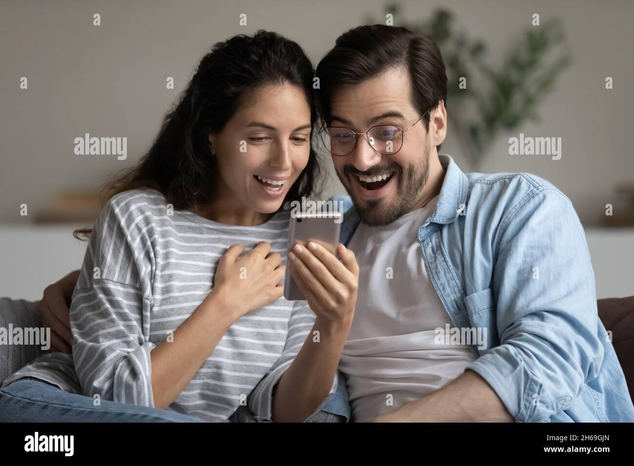 Tête de prise de vue couple excité regardant l'écran de smartphone, la lecture des nouvelles Banque D'Images