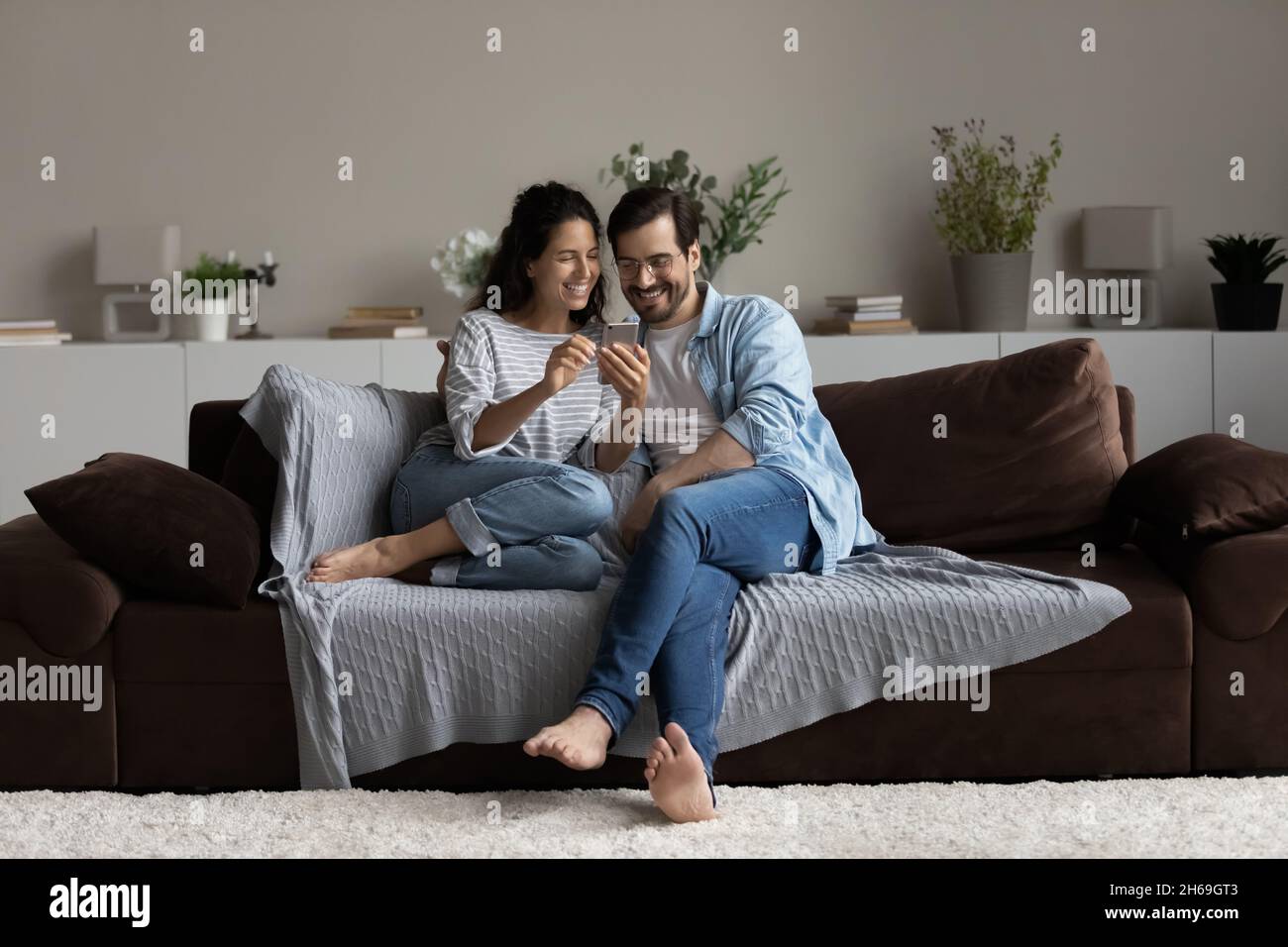 Un jeune couple heureux s'amuser avec un smartphone à la maison Banque D'Images