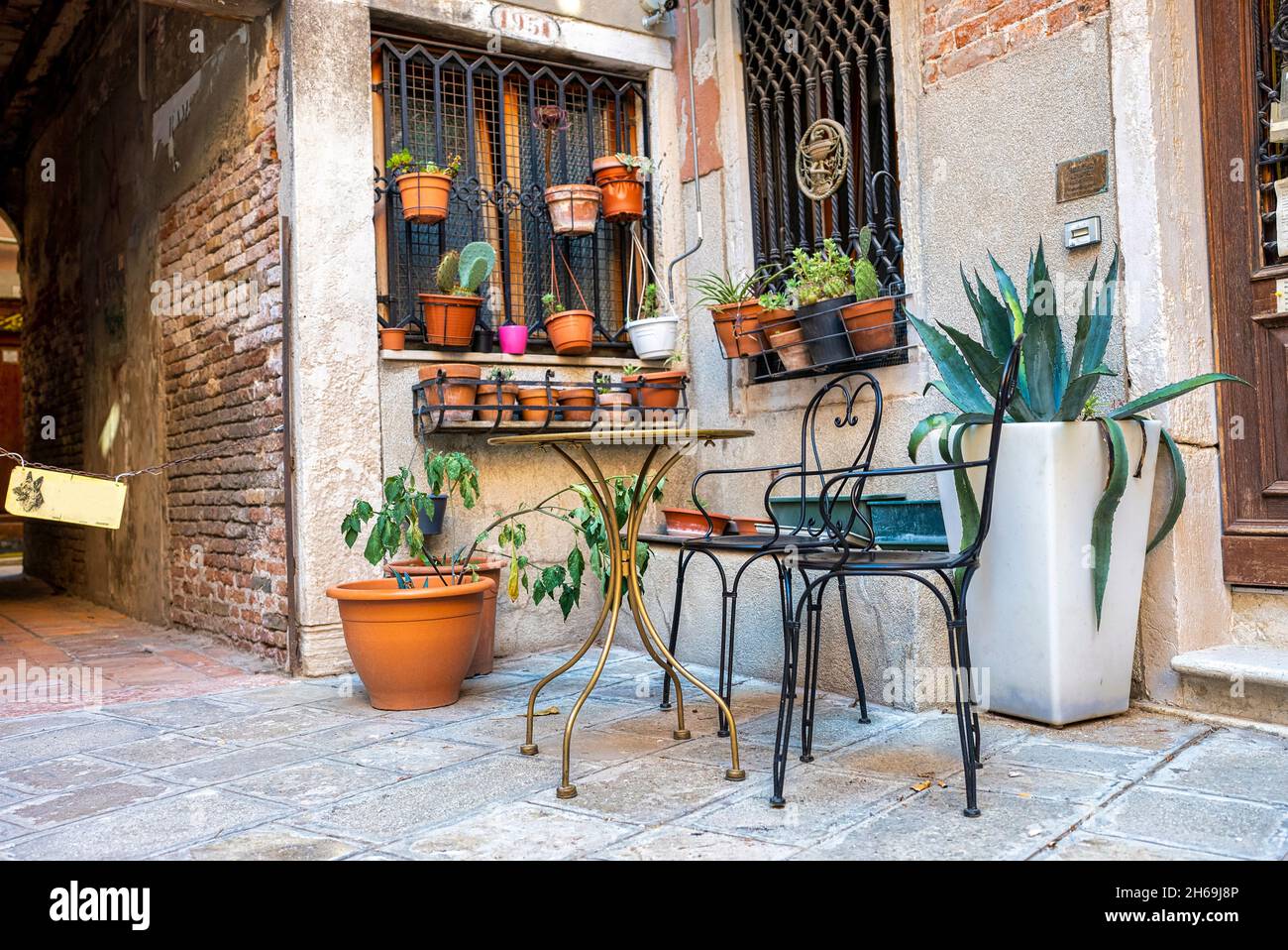 Maison traditionnelle avec plantes en pot sur une fenêtre en brique avec chaises et tables à l'extérieur Banque D'Images