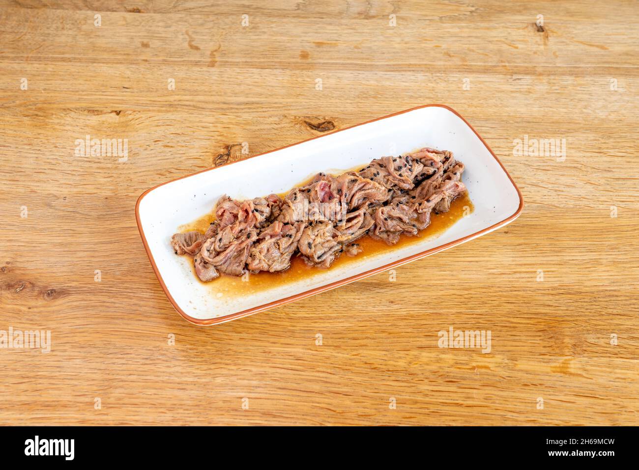 Le sashimi est un plat japonais qui se compose principalement de fruits de mer crus ou de poisson, finement coupés, mais pas autant qu'un carpaccio.Servi avec une sauce et Banque D'Images