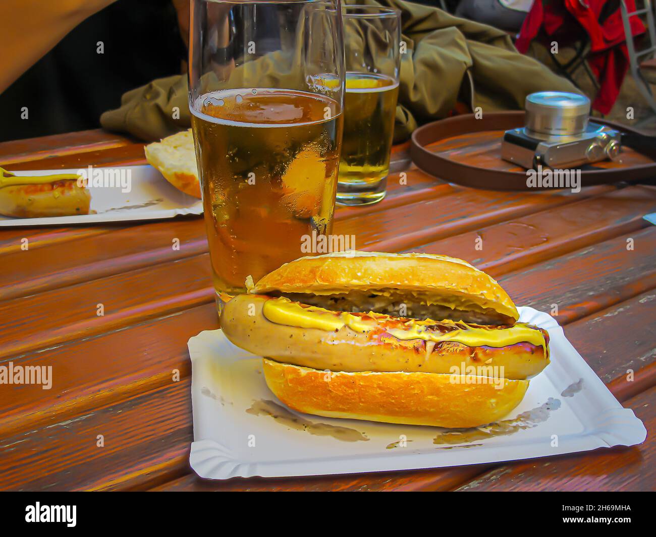 Délicieux hot dog avec beaucoup de moutarde, servi avec des chopps de glace, à une happy hour, après avoir pris des photos dans la ville. Banque D'Images