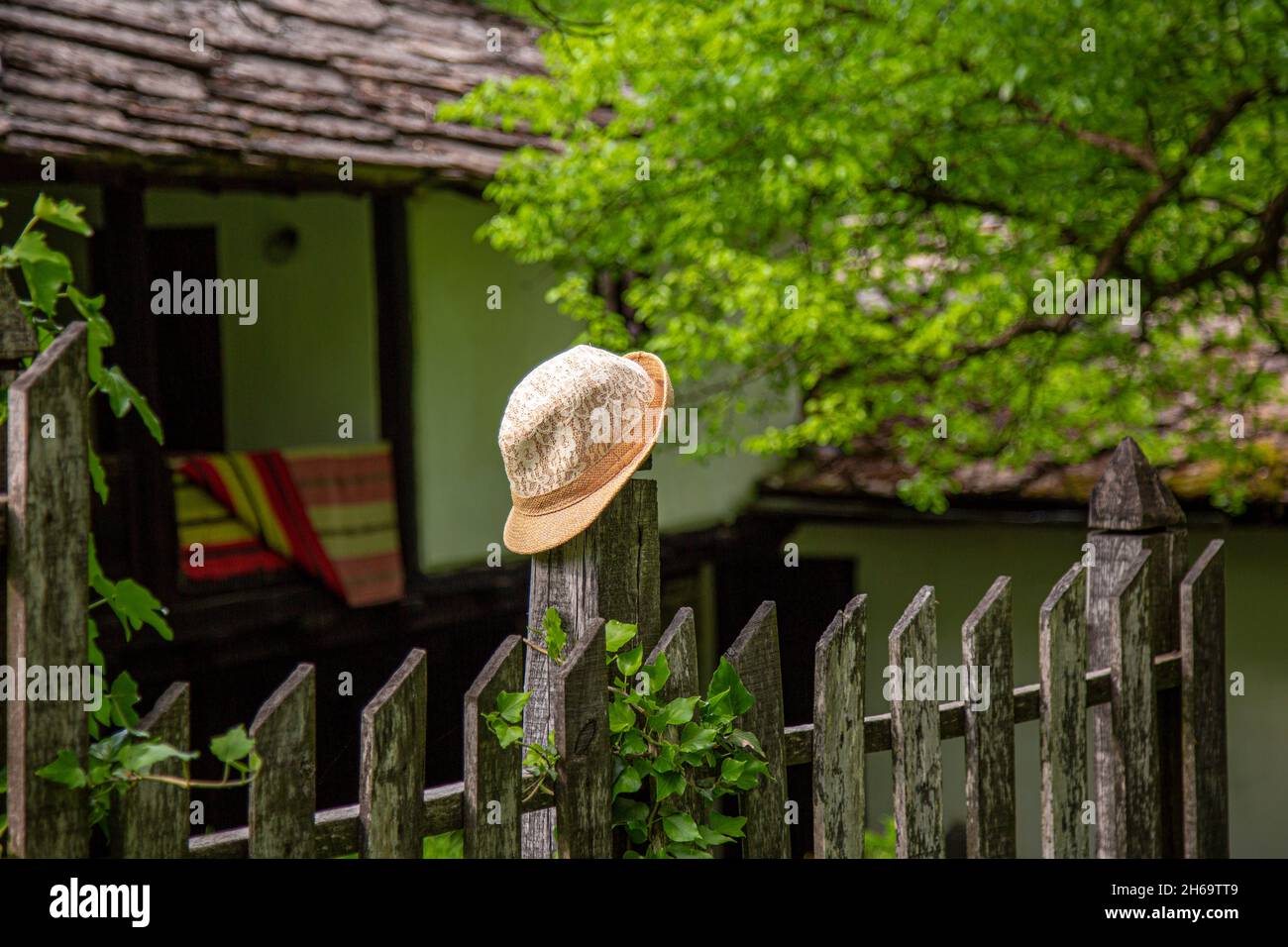 Un chapeau de femme jaune de paille reposant sur un poste de clôture avec des terres agricoles à l'arrière-plan dans le village bulgare. Banque D'Images