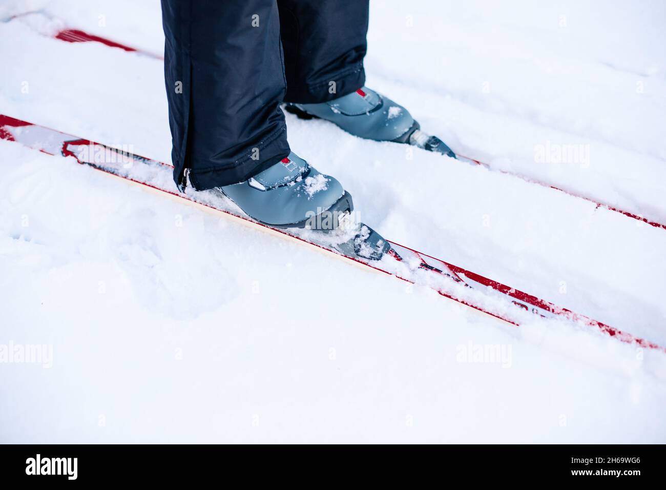 Gros plan des jambes avec des chaussures de ski grises sur les skis.Homme skier sur la neige d'hiver par beau temps, vue latérale Banque D'Images