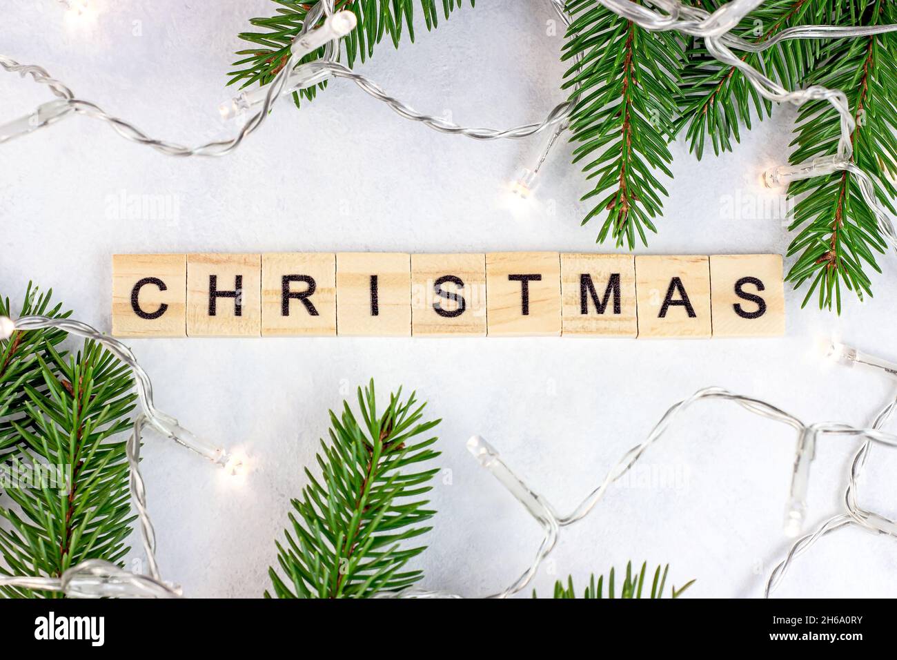 Vue de dessus du texte de Noël en bois avec branches de sapin vert et lumières comme décoration de saison de Noël sur fond blanc pour les cartes de vœux.Traditio Banque D'Images Vue de dessus du texte de Noël en bois avec branches de sapin vert et lumières comme décoration de saison de Noël sur fond blanc pour les cartes de vœux.Traditio Banque D'Images