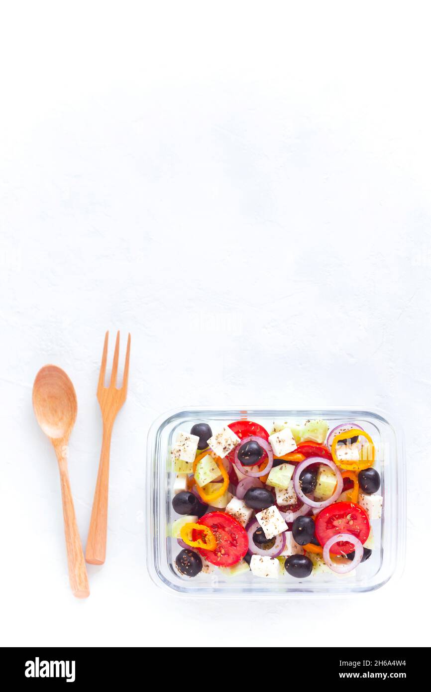 contenant avec salade grecque, coutellerie en bois, sur fond blanc, vue de dessus, espace de copie,concept de nourriture saine et zéro gaspillage Banque D'Images