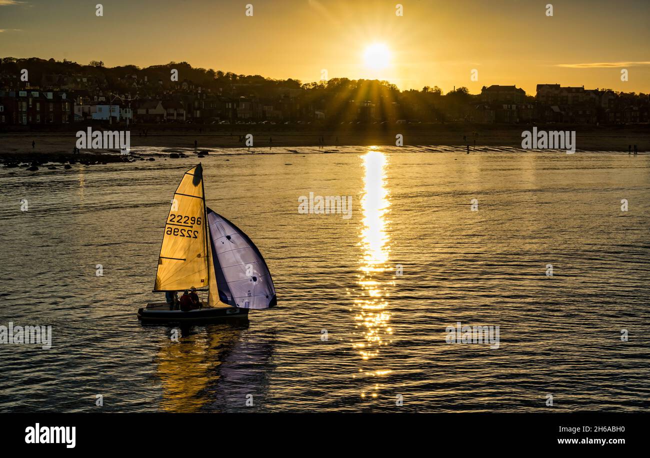 Un canot pneumatique au coucher du soleil avec une lumière qui traverse l'eau dans West Bay à North Berwick, East Lothian, Écosse, Royaume-Uni Banque D'Images