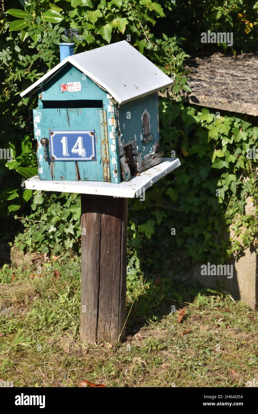 Une boîte aux lettres faite maison, une boîte en bois peinte en turquoise sous la forme d'une maison avec un toit incliné et l'ensemble de l'ouverture avant sur charnière à piano Banque D'Images