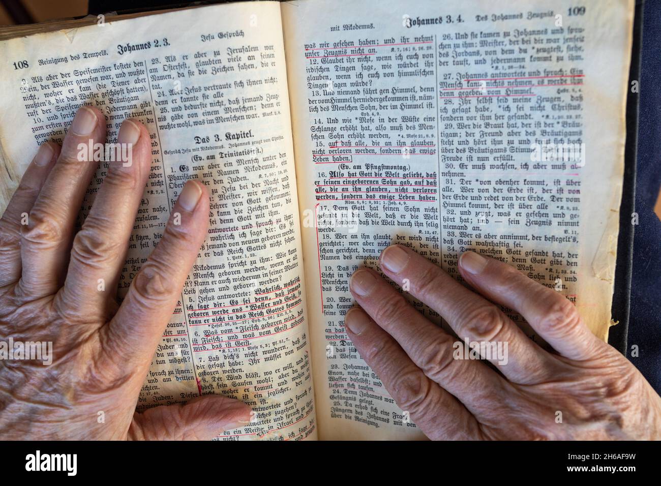 Ma mère/grand-mère de 94 ans, lit dans sa Bible Jean 3:16. Vieux script allemand.Le concept des enseignements de Jésus. Banque D'Images