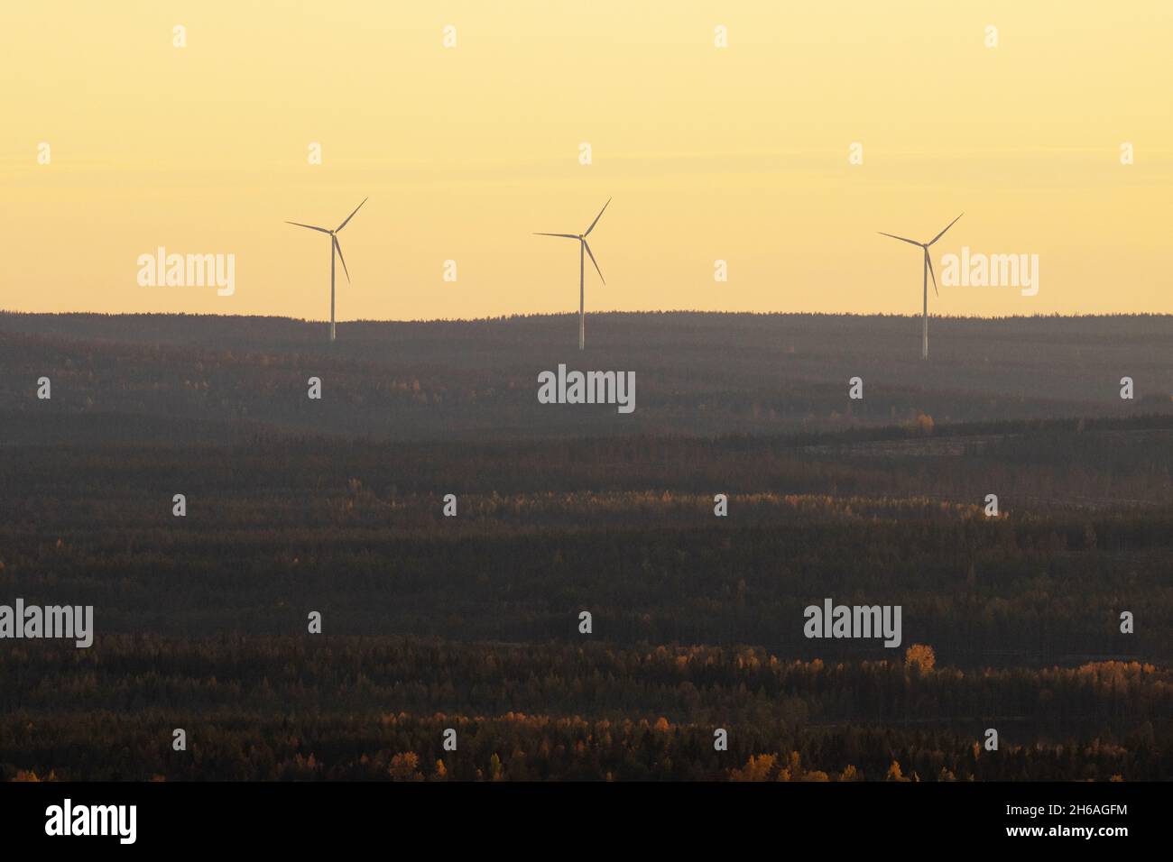 Trois éoliennes travaillant dans le nord de la Finlande pendant une soirée sombre. Banque D'Images