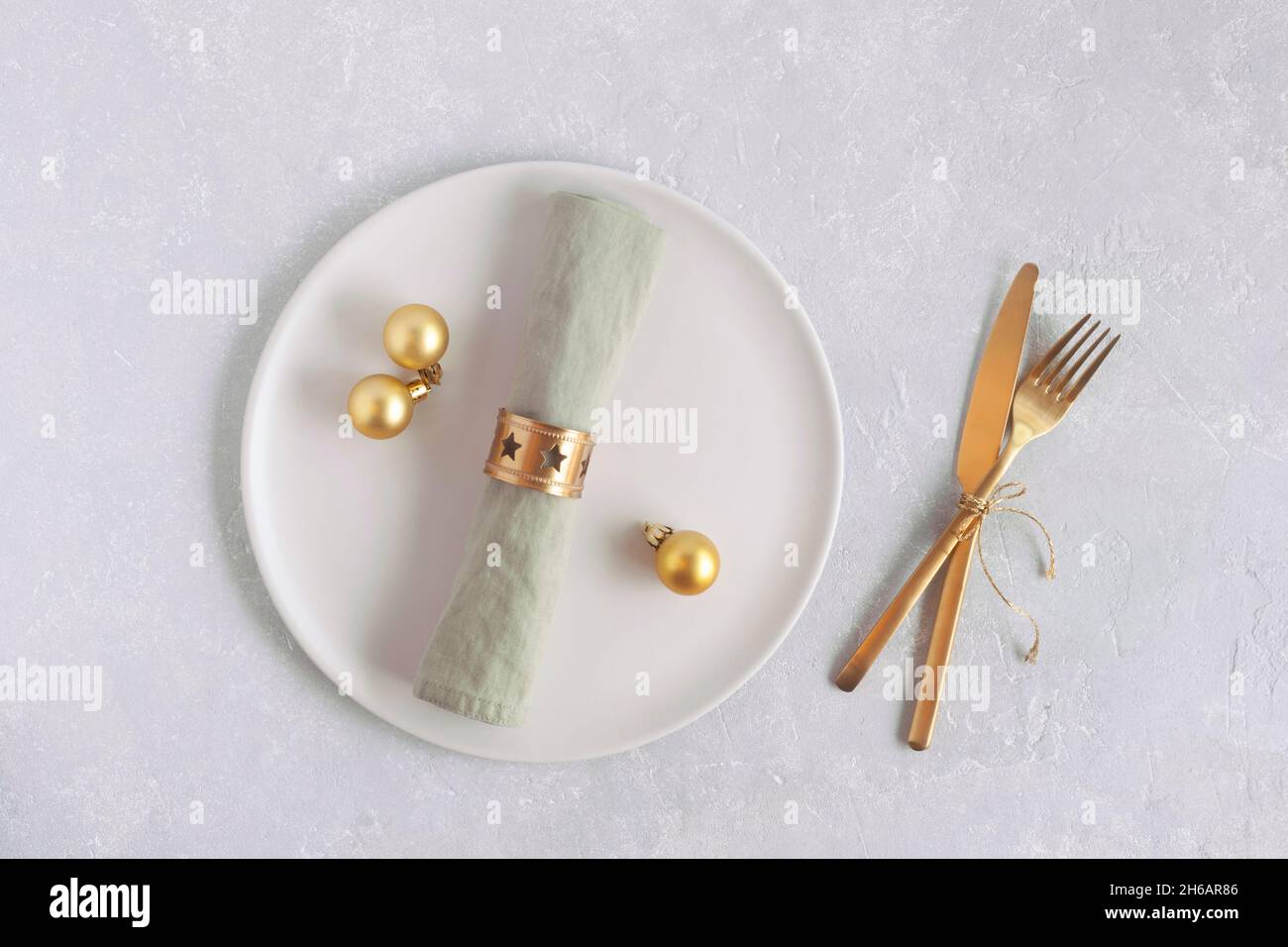 assiette et couverts pour le dîner du nouvel an, vue sur le dessus, couleurs dorées, sur fond gris Banque D'Images