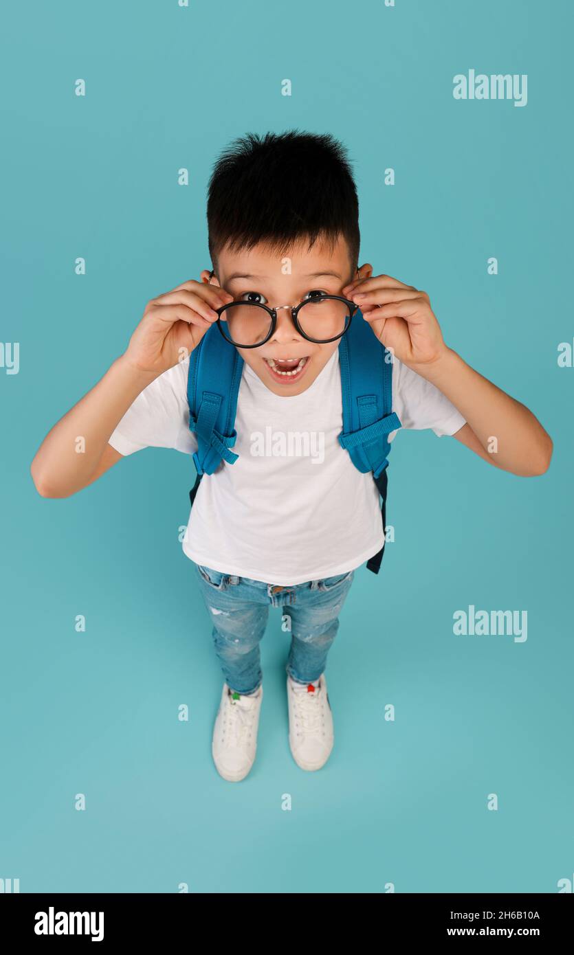 Offre d'étude.Drôle d'écolier coréen portant des lunettes de vue regardant la caméra avec excitation, surpris Asian Kid émotionnellement réagir aux nouvelles pendant que Stand Banque D'Images