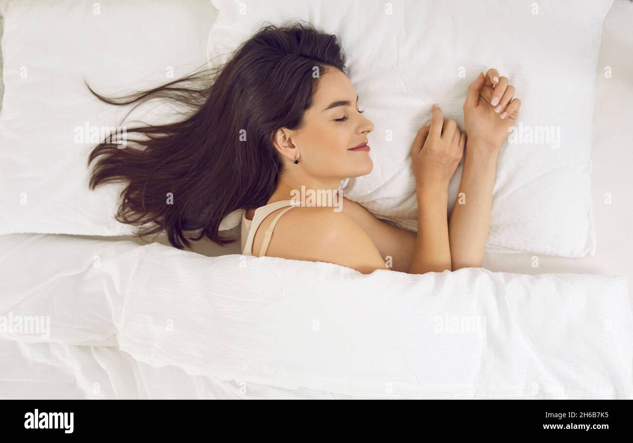 Vue depuis le dessus de la belle jeune femme détendue dormant sur un oreiller blanc dans son lit Banque D'Images