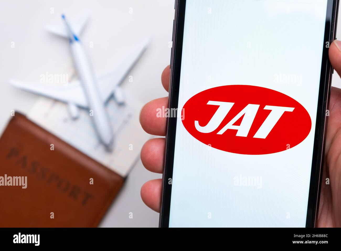 Application ou logo de la société JAT Airlines affiché sur un téléphone portable avec passeport, carte d'embarquement et avion en arrière-plan, septembre 2021, San Francisco, États-Unis. Banque D'Images