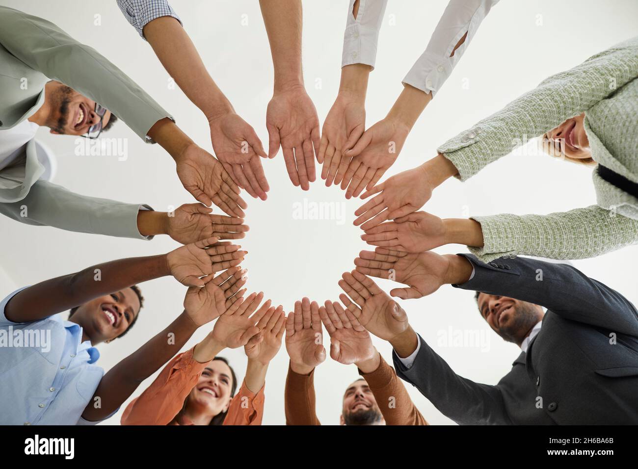 Groupe de gens d'affaires multiraciaux heureux se joignant à la main pour démontrer l'unité et la solidarité. Banque D'Images