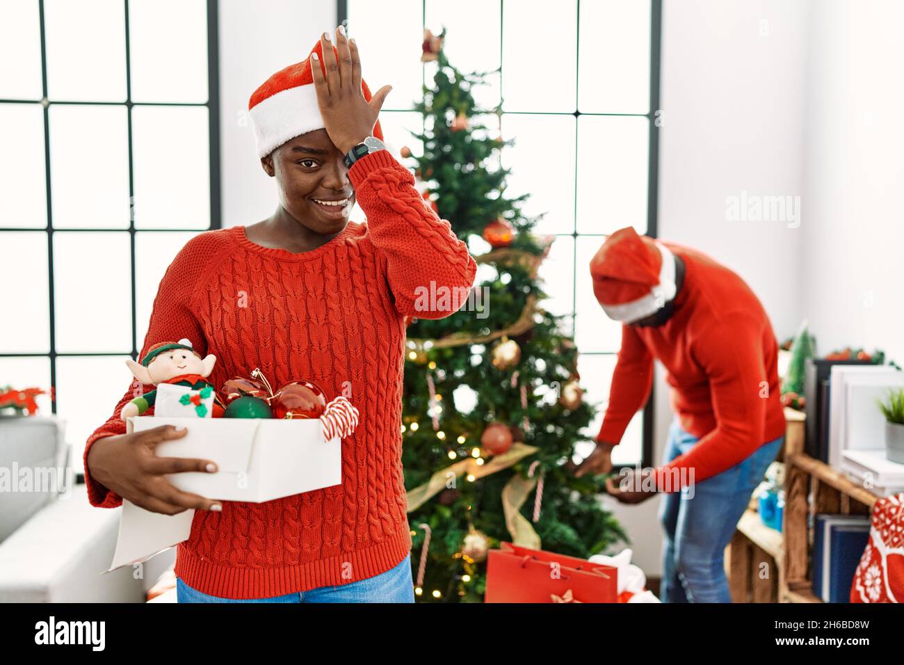 Un jeune couple afro-américain debout près d'un arbre de noël surpris par la main sur la tête pour l'erreur, souvenez-vous de l'erreur. oublié, mauvais concept de mémoire. Banque D'Images Un jeune couple afro-américain debout près d'un arbre de noël surpris par la main sur la tête pour l'erreur, souvenez-vous de l'erreur. oublié, mauvais concept de mémoire. Banque D'Images