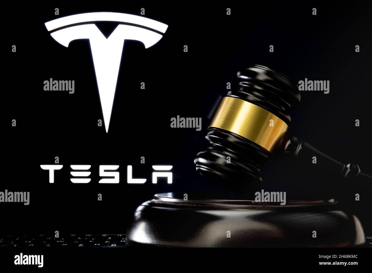 Le gavel du juge devant et le logo flou de la société Tesla vu à l'écran derrière.Concept.Stafford, Royaume-Uni, 14 novembre 2021. Banque D'Images