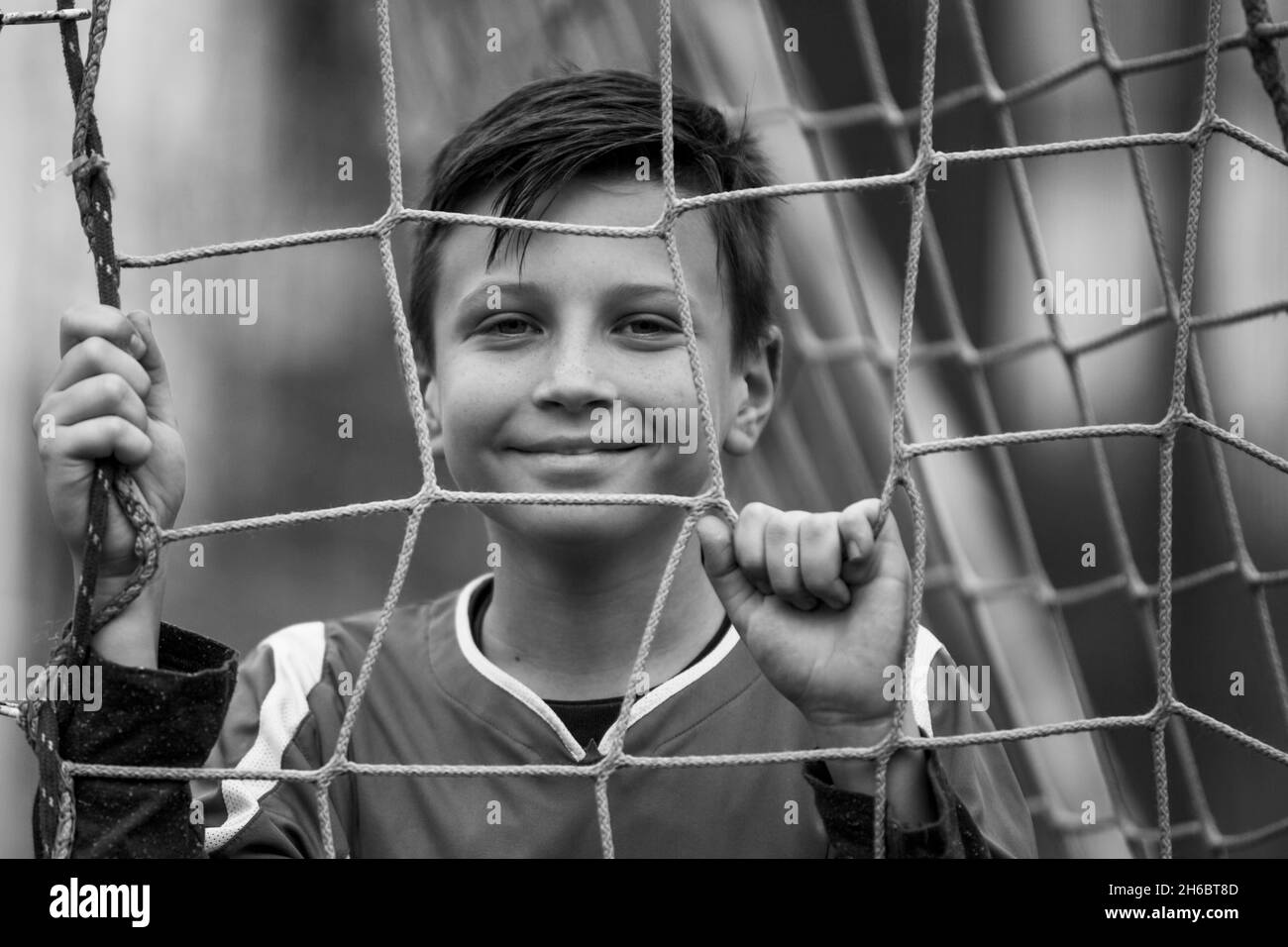 Un jeune garçon près d'un but sur le terrain de football.Photo en noir et blanc. Banque D'Images