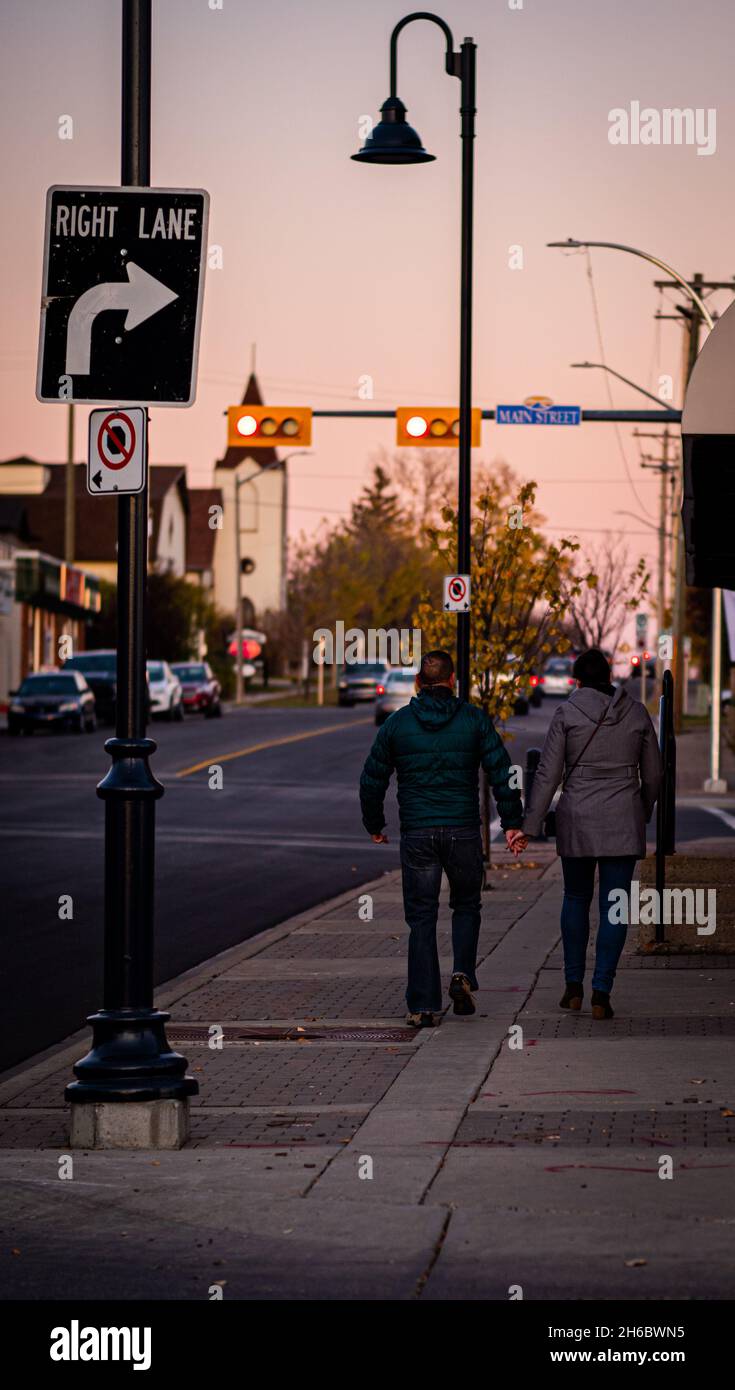 Une photo verticale d'un couple qui marche ensemble sur le trottoir en tenant les mains juste avant que le soleil ne tombe Banque D'Images