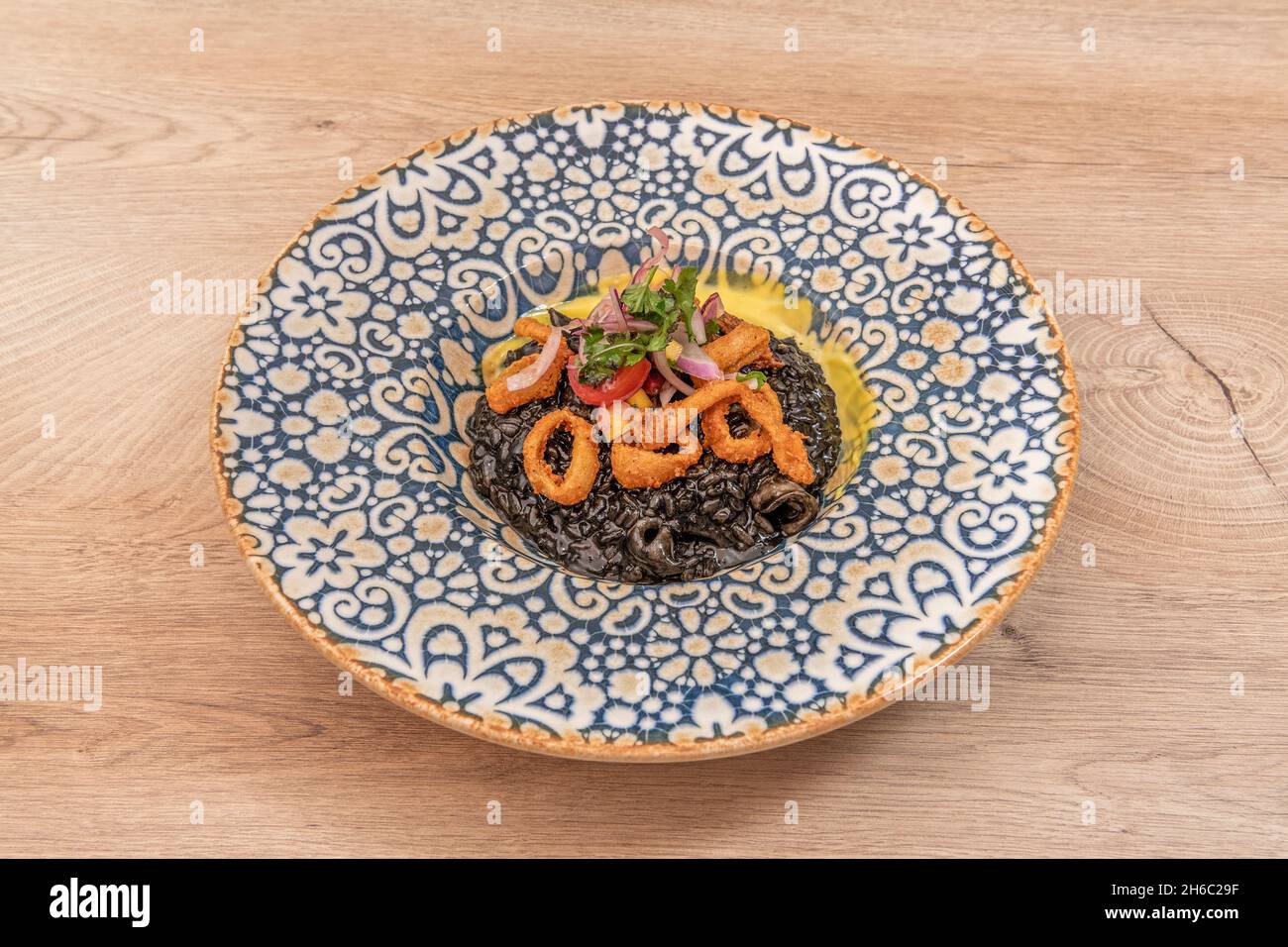 Risotto de calamar nero mâché d'oignon rouge et de rondelles de calamars  battues sur une assiette en porcelaine décorée en bleu et blanc Photo Stock  - Alamy