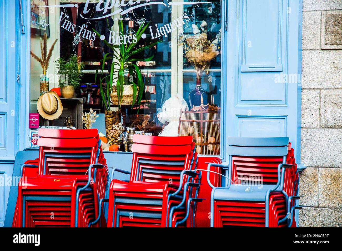 Carte postale joli extérieur d'un bar et café à Auray, Bretagne, France.Chaises rouges contre des volets bleus.Style de vie français. Banque D'Images