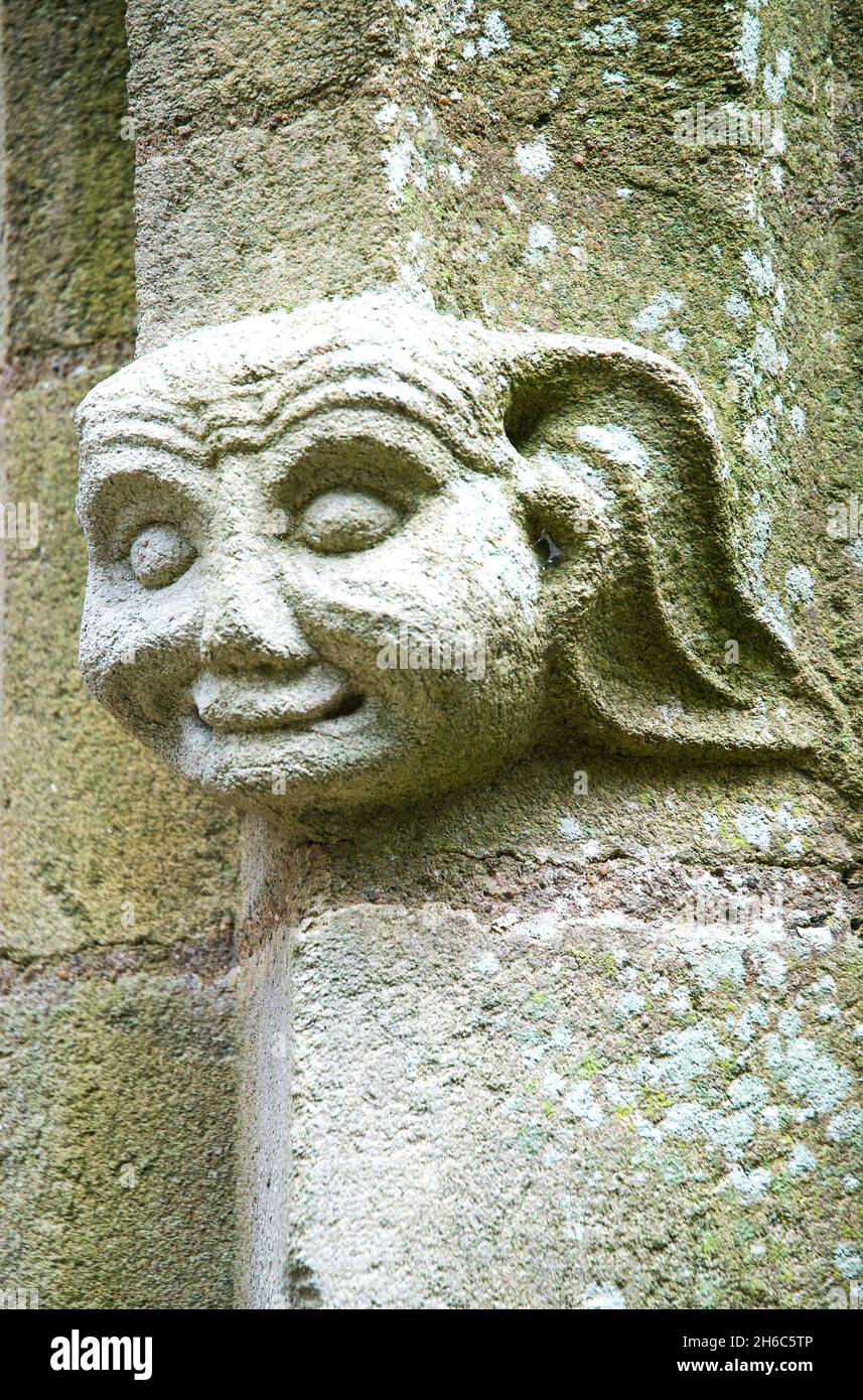 Un visage sculpté serein est visible sur une colonne de pierre extérieure aux ruines de la partie du XIe siècle de l'église Saint-Saveur à Locmine, Bretagne, Banque D'Images