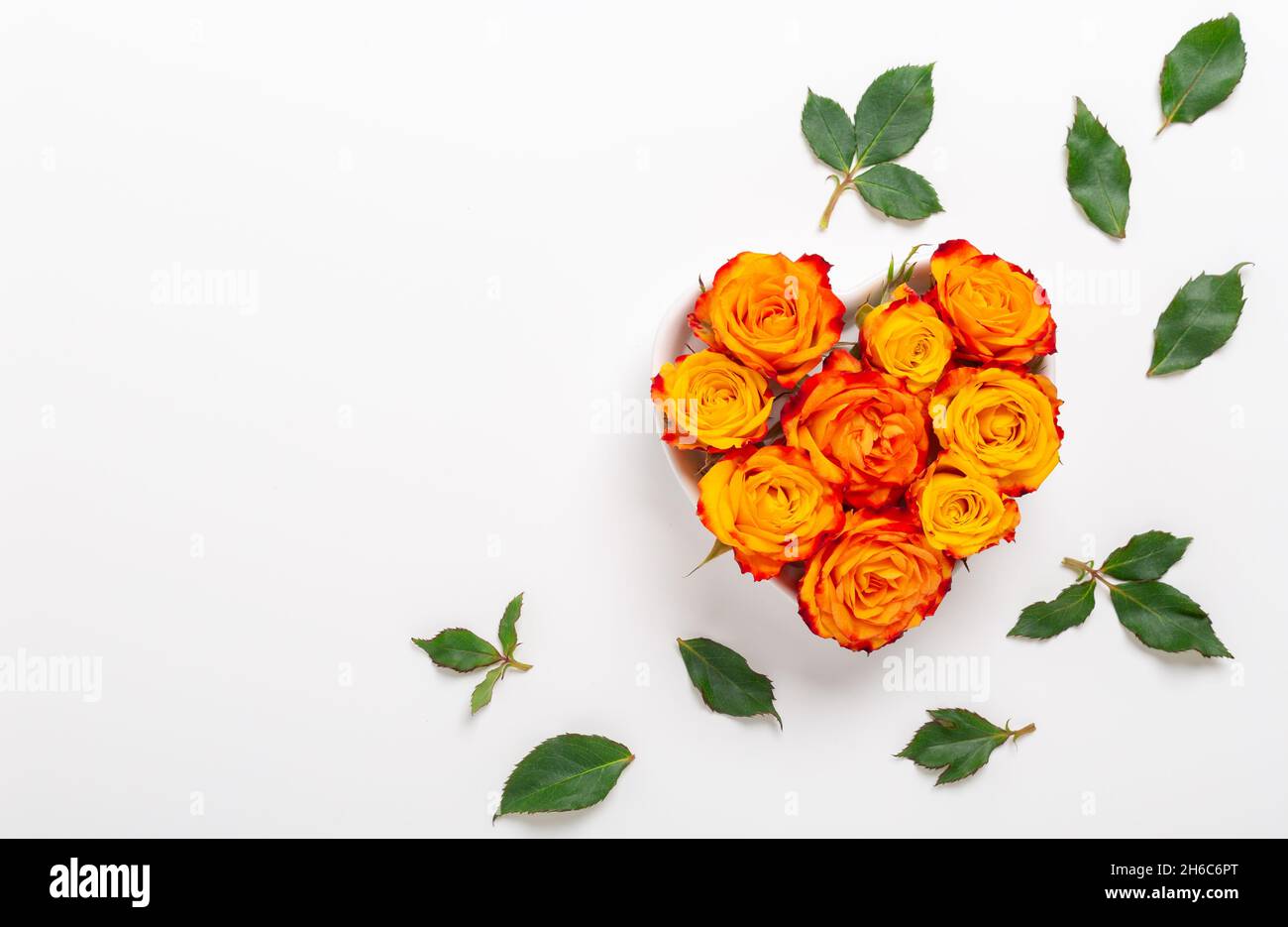 Composition des fleurs. Fleurs roses orange dans un bol en forme de coeur sur fond blanc. Concept de la Saint-Valentin. Flat lay, vue de dessus, espace de copie - image Banque D'Images