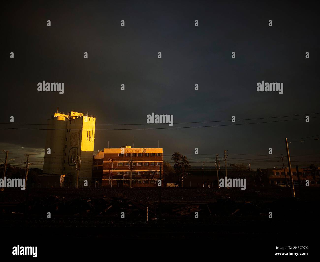 Une usine située dans une zone industrielle de Melbourne, en face d'une ligne de train, éclairée par le coucher de soleil doré pendant l'heure d'or à West Footscray, en Australie. Banque D'Images