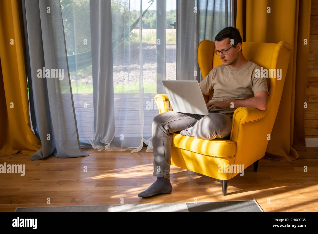 Un endroit confortable pour travailler à la maison.Un homme travaille dans un grand fauteuil jaune Banque D'Images