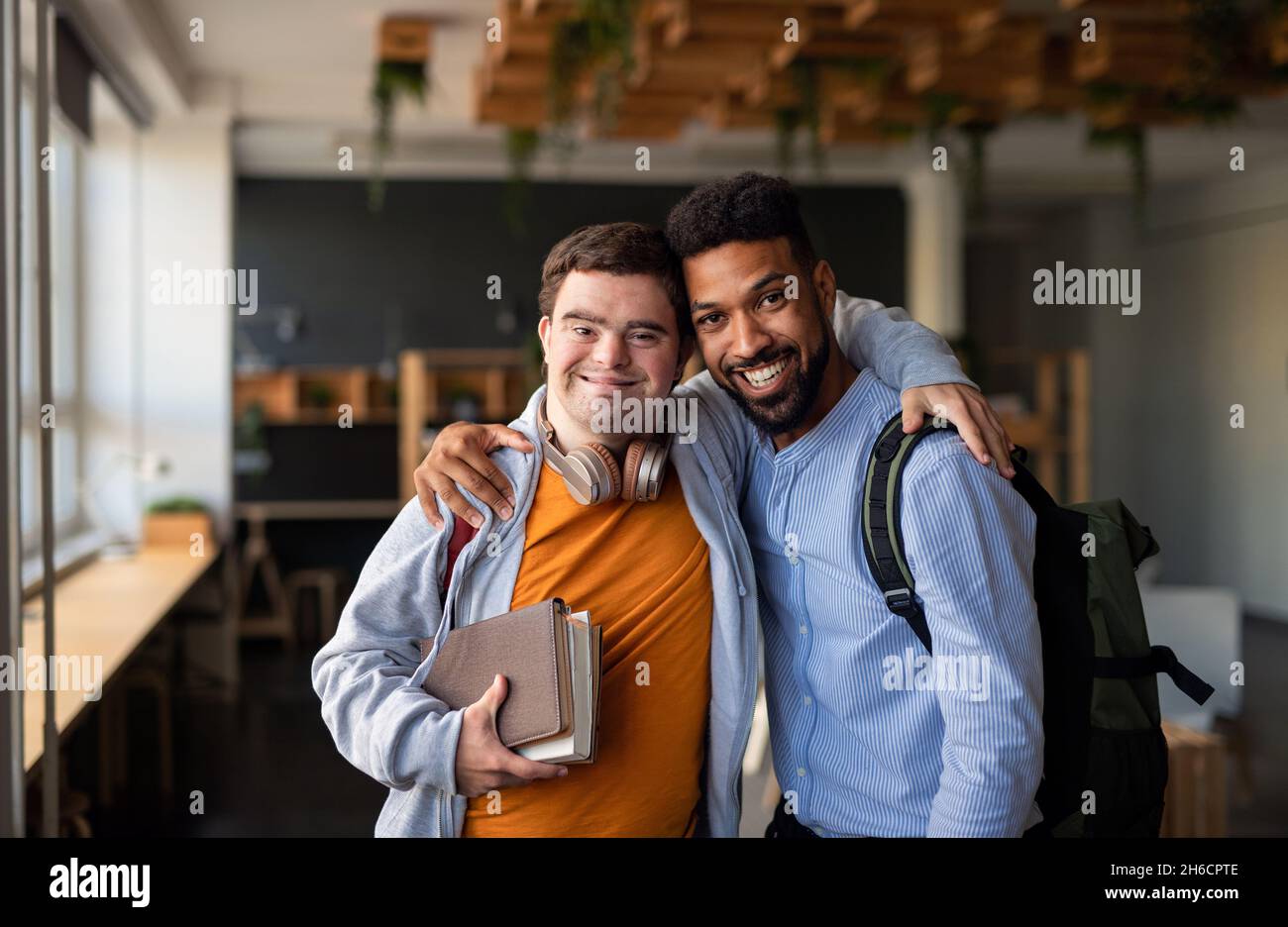 Jeune homme avec le syndrome de Down et son tuteur avec les bras autour de regarder la caméra à l'intérieur à l'école Banque D'Images