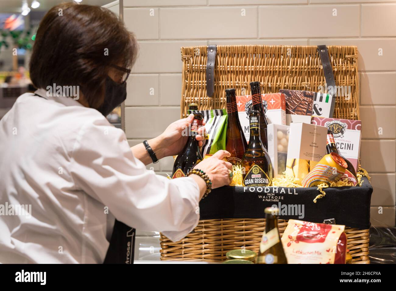 Une dame prépare un panier de Noël rempli de vins, chocolats, fromage, pour la fête de l'Angleterre Banque D'Images