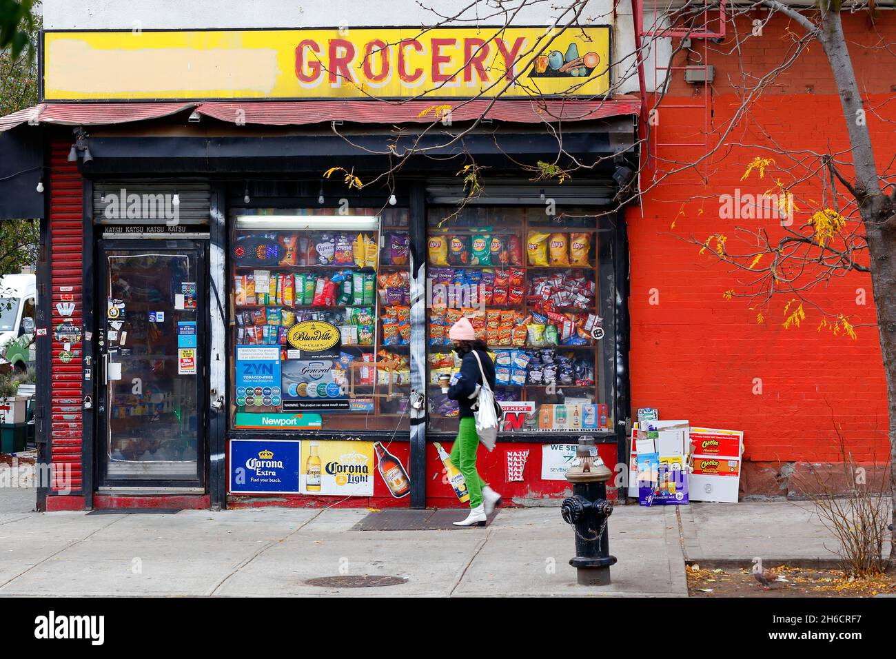 Une personne de la génération Z marche à côté d'une épicerie deli bodega dans le quartier de Wililamsburg à Brooklyn, New York Banque D'Images