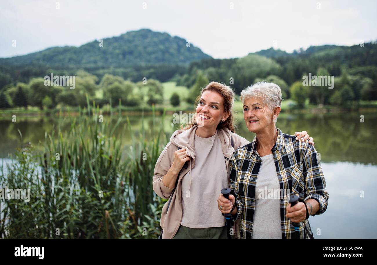 Bonne mère aînée embrassant avec une fille adulte en se tenant au bord du lac à l'extérieur dans la nature Banque D'Images