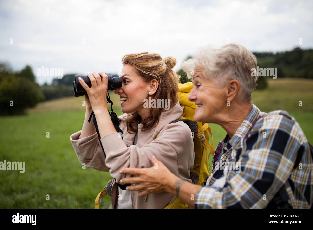 Bonne mère randonneur avec fille adulte regardant à travers des jumelles à l'extérieur dans la nature Banque D'Images