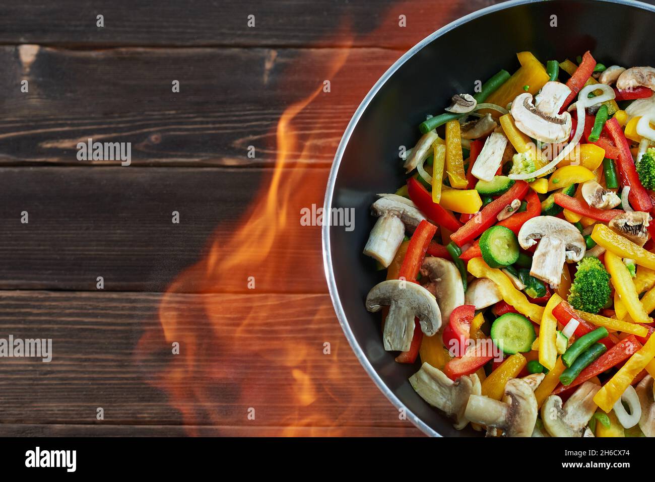 Poêle wok avec légumes sur fond de bois, vue de dessus.Wok de légumes - poivrons, oignons, petits pois, champignons, haricots,brocoli, courgettes.Cuisine asiatique.Menton Banque D'Images