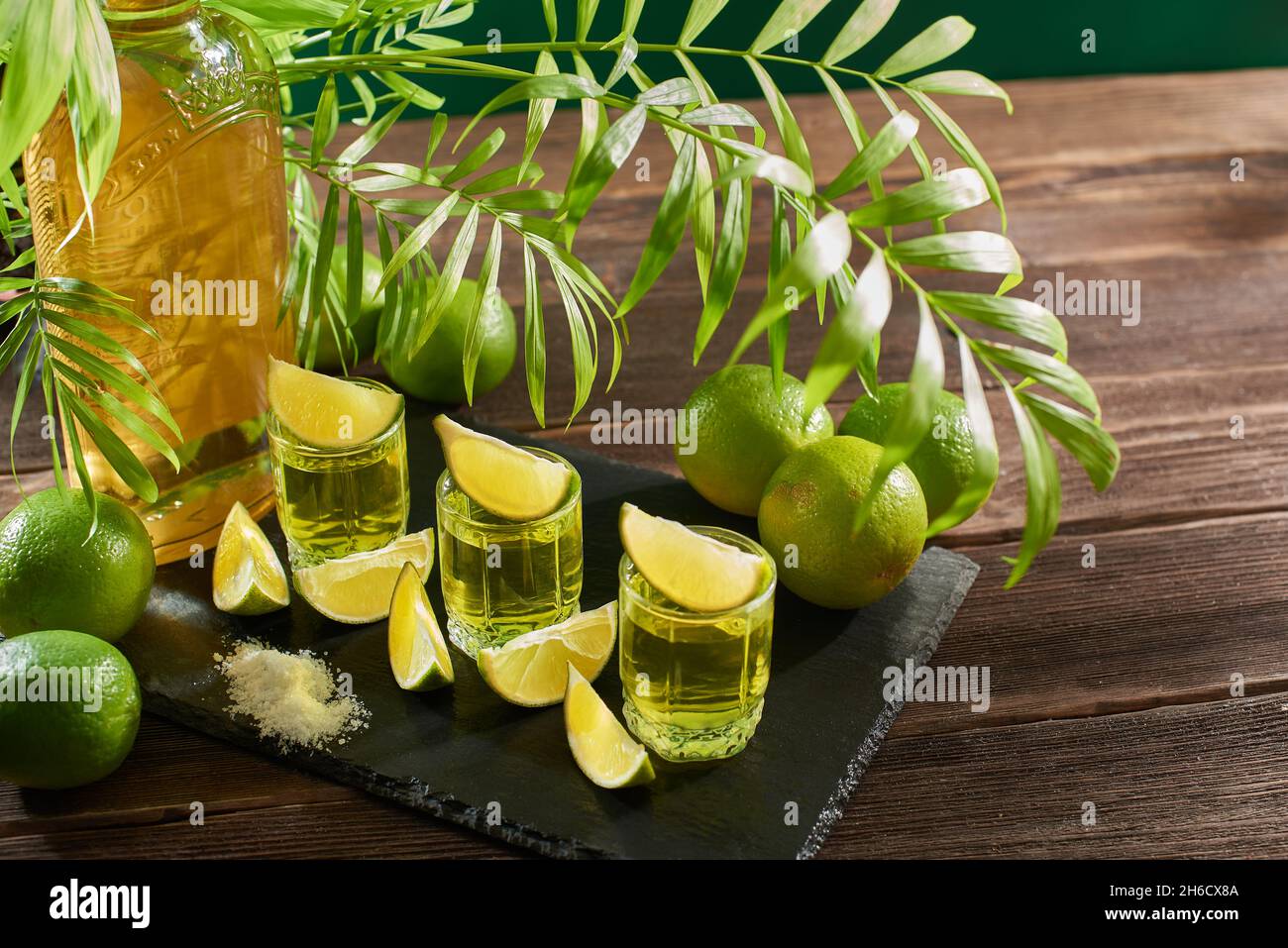 Bouteille et verres de tequila au citron vert sur une table en bois.Boisson alcoolisée mexicaine traditionnelle.Cocktail alcoolisé au citron vert.La boisson de gin est serv Banque D'Images