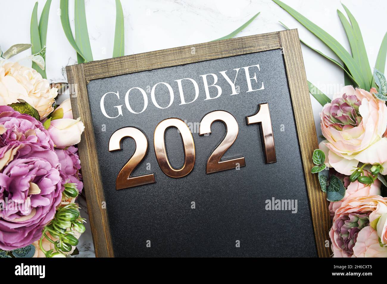 Au revoir 2021 texte sur tableau noir avec décoration florale sur fond de marbre Banque D'Images