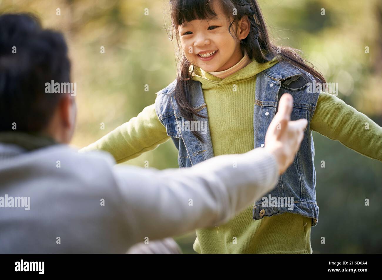 un jeune père asiatique embrasse une fille de 4 ans à l'extérieur dans un parc heureux et souriant Banque D'Images