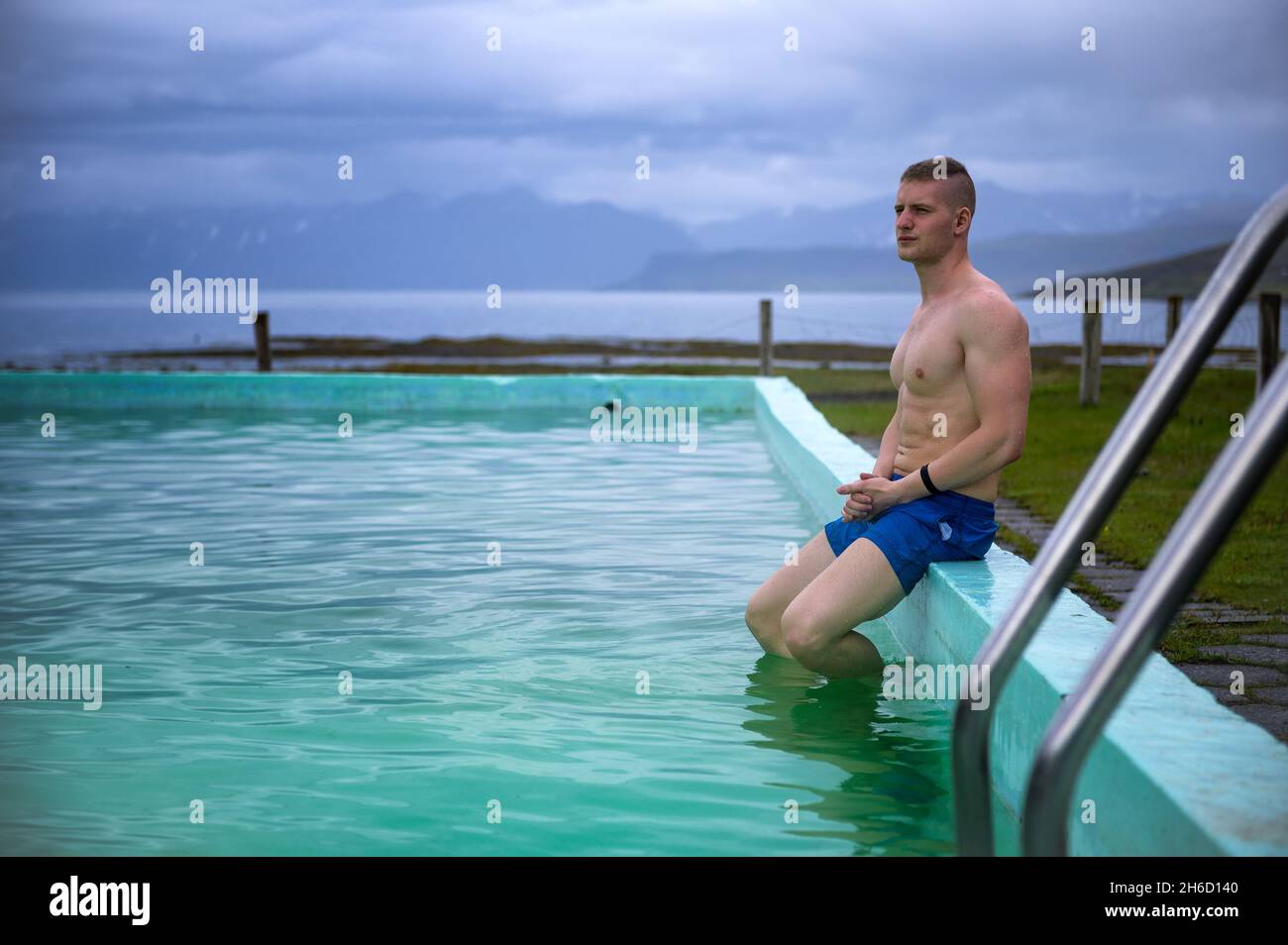 Un garçon se baigne dans la piscine chaude de Reykjafarlaug, située dans la Westfjords, en Islande Banque D'Images