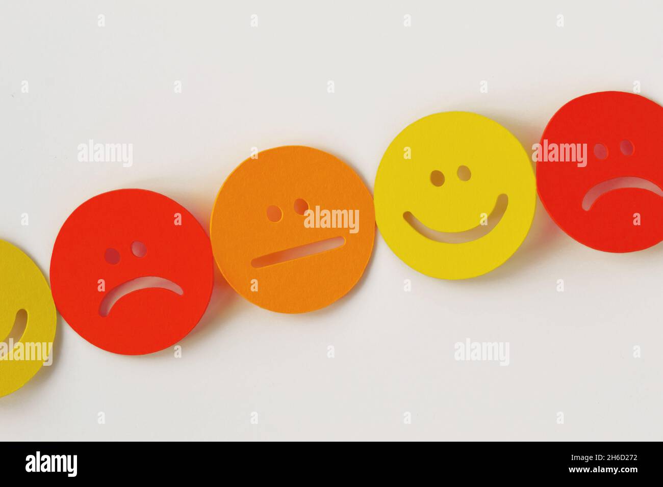 Chaîne de faces de papier jaune, orange et rouge avec expression positive, neutre et négative sur fond blanc Banque D'Images
