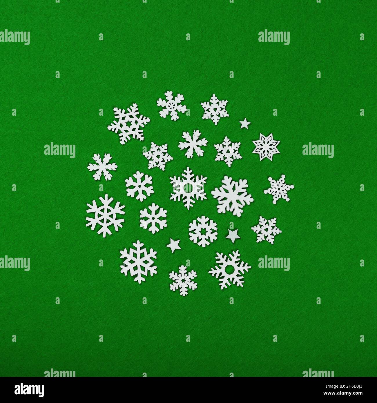 Gros plan cercle de flocons de neige en bois blanc décoration de Noël sur fond de feutre vert, vue sur le dessus de la table, plat Banque D'Images