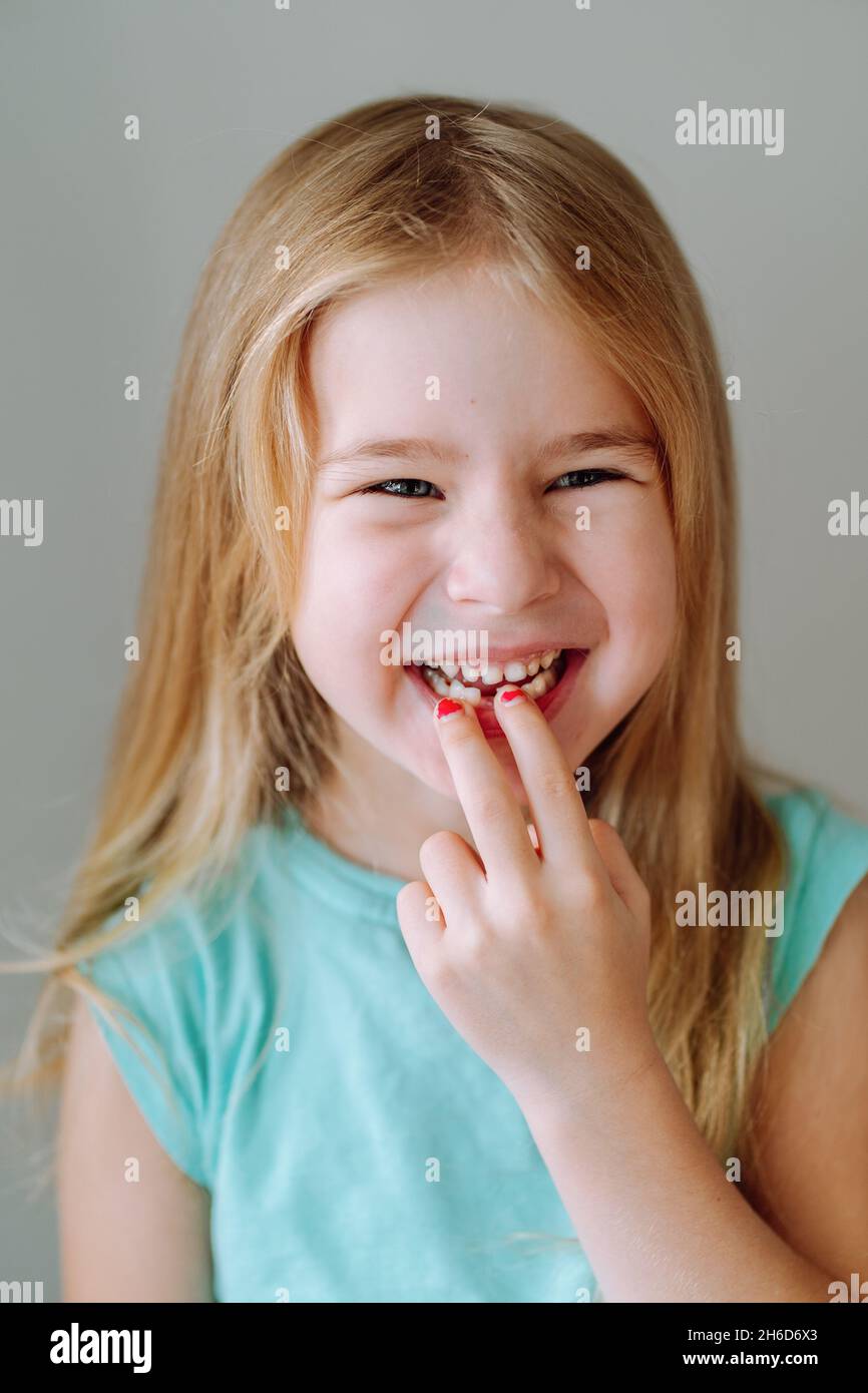 Portrait d'une jeune fille d'âge préscolaire souriant et montrant sa bouche avec une dent de lait tombée.Hygiène dentaire, fée dentaire. Banque D'Images