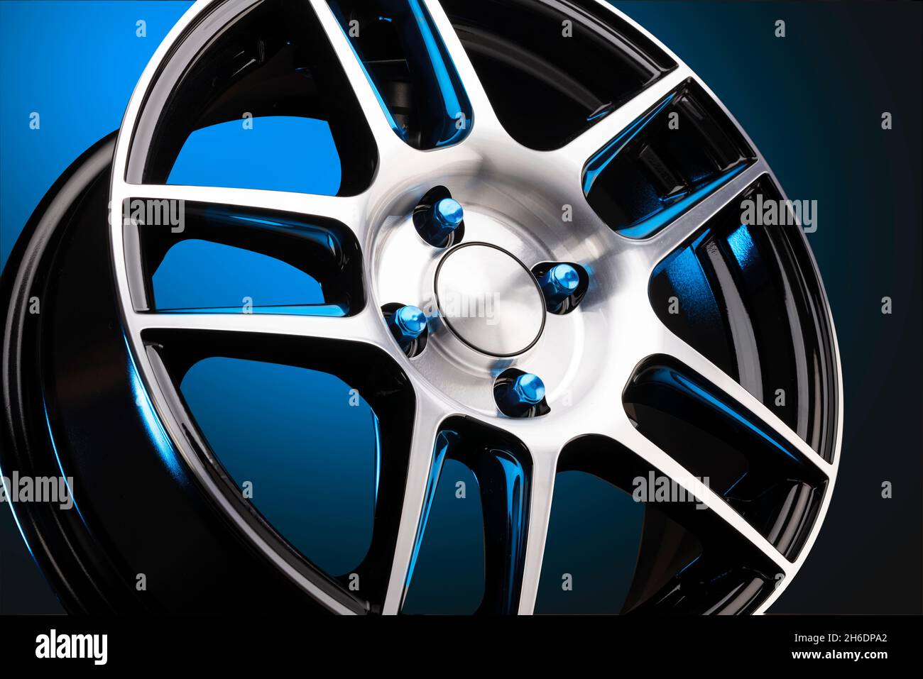 nouvelle roue en alliage légère et sportive avec écrous en acier bleu sur fond bleu dégradé, un magnifique concept auto pour un magasin de pneus ou de disques. Banque D'Images