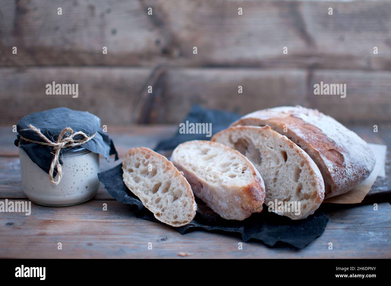Faire cuire des tranches de pain au levain à côté d'un pot avec une culture de départ vivante Banque D'Images