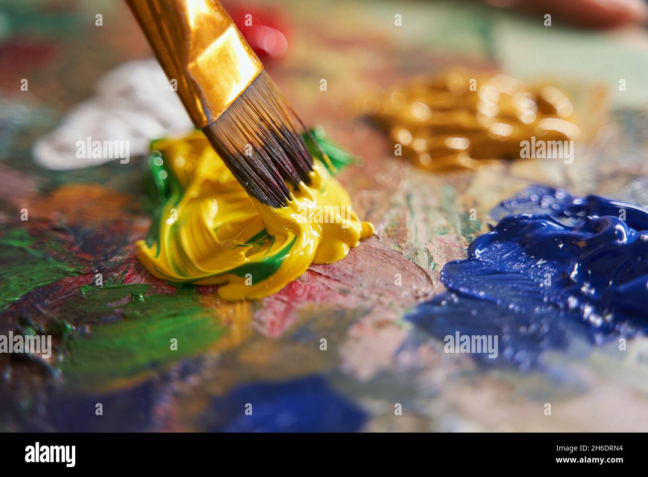Peintre mélange de peintures jaunes et vertes avec un pinceau Banque D'Images