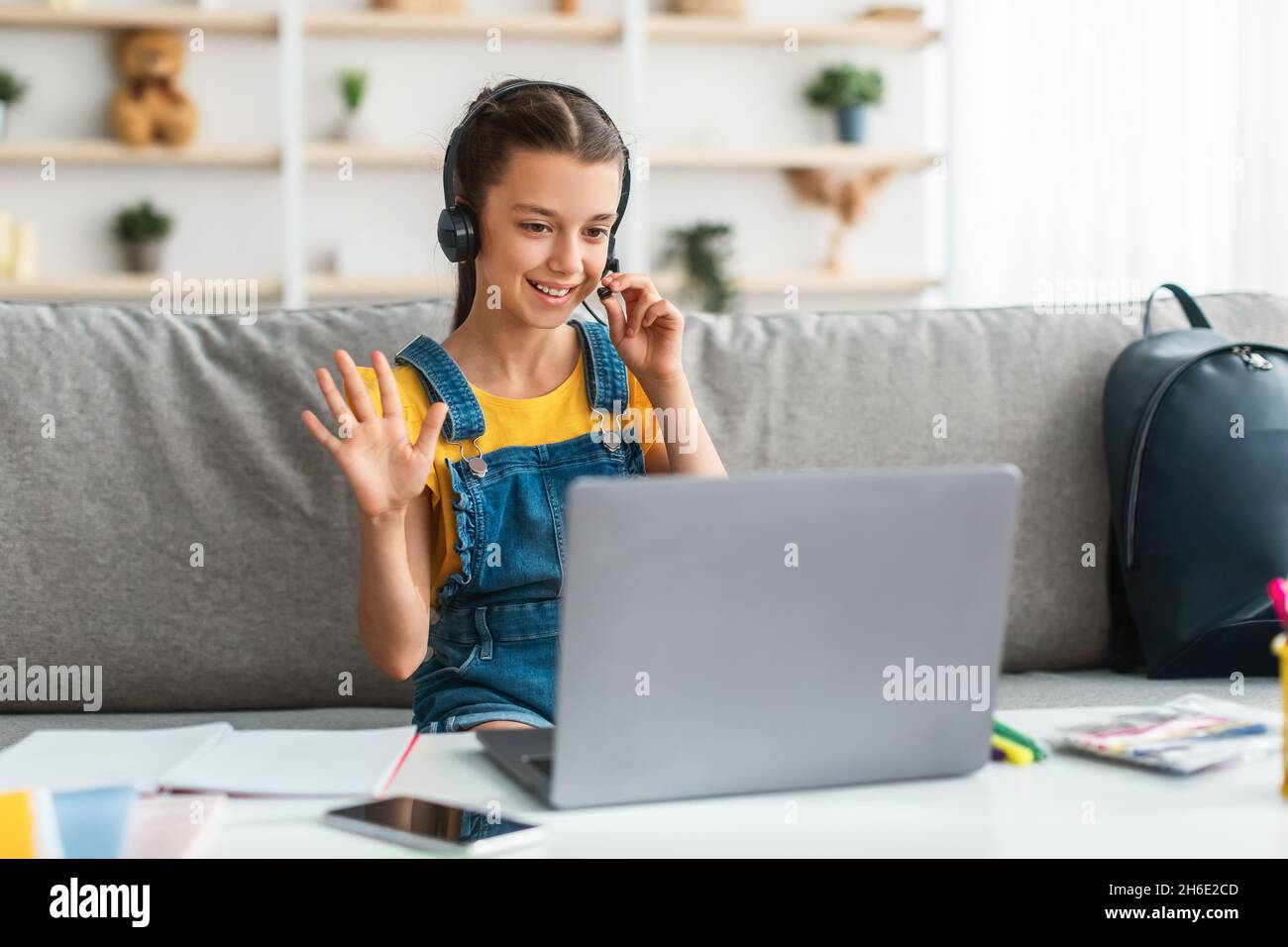 Fille dans un casque utilisant un ordinateur portable, en agitant à la webcam Banque D'Images