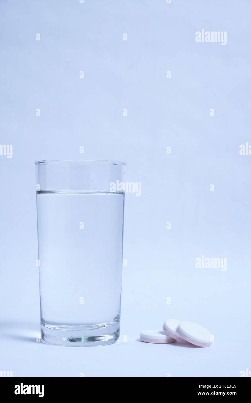 Verre d'eau propre et des pilules sur fond gris Banque D'Images